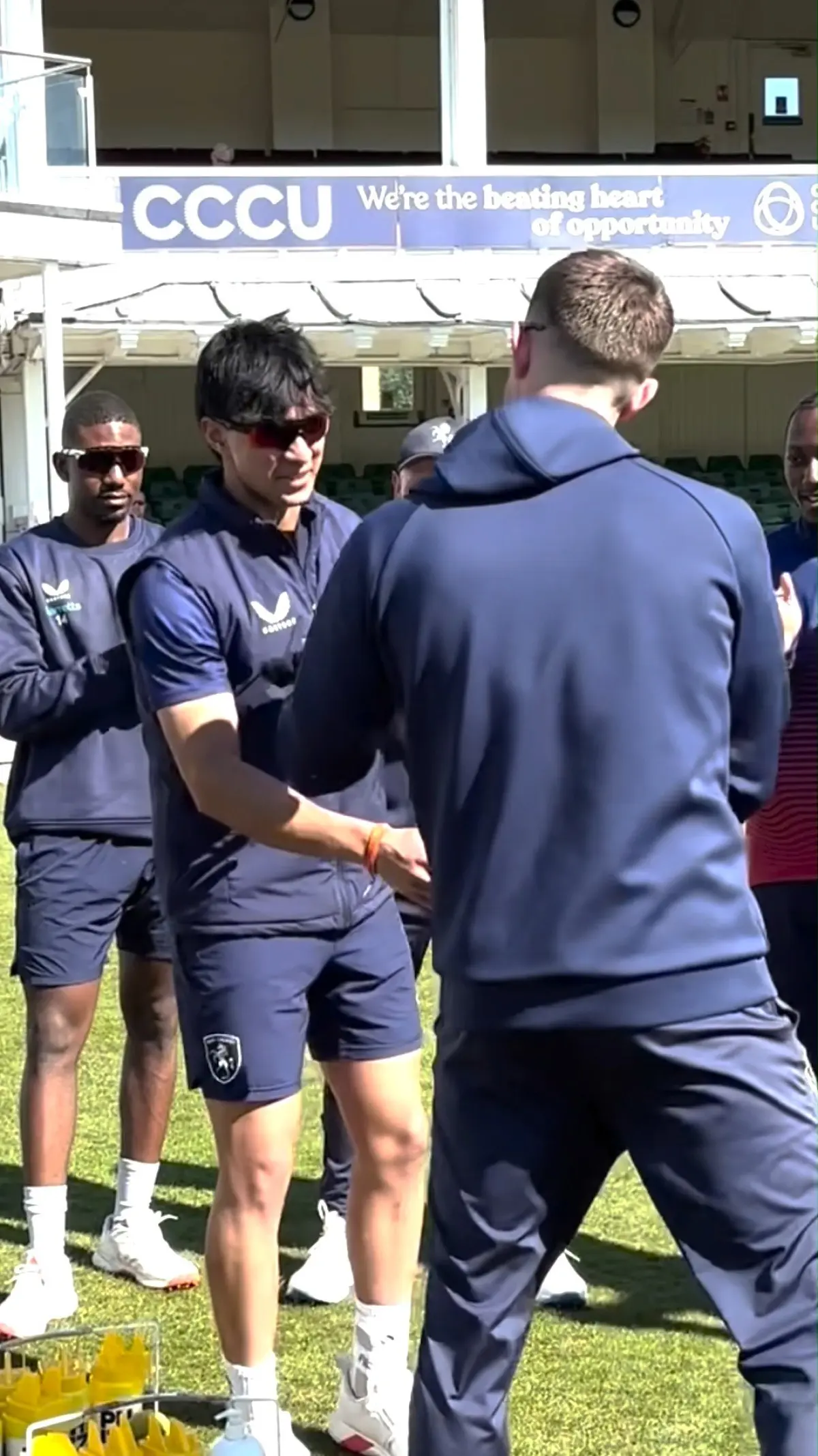 Seasoned cricketer celebrates debutant's achievement with a symbolic debut cap gesture.